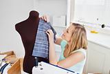 Delighted young woman sewing clothes at home