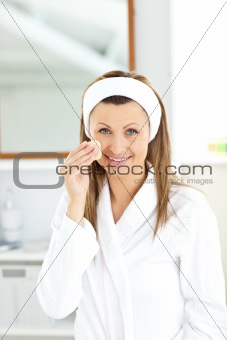 Cheerful woman putting foundation cream in her bathroom