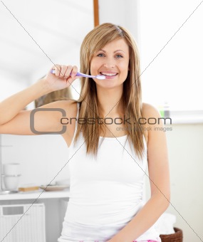 Glowing blond woman brushing her teeth in the bathroom