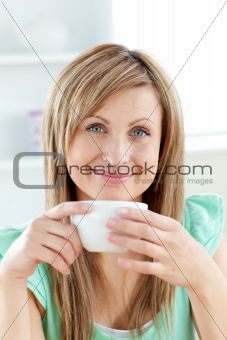 Bright woman holding a cup of coffee in the kitchen