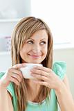 Smiling woman holding a cup of coffee in the kitchen