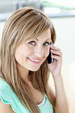 Happy young woman talking on phone smiling at the camera in the 