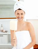Merry woman with towels holding a brush in the bathroom