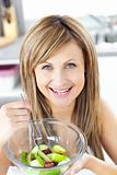 Smiling woman eating a fruit salad smiling at the camera in the 