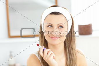 Caucasian young woman using a red lipstick in the bathroom