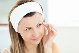 Pretty woman putting cream on her face wearing a headband in the