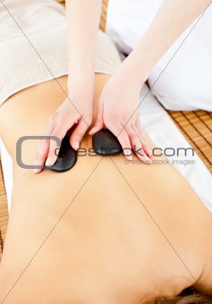 Close-up of a young woman receiving a back massage with hot ston