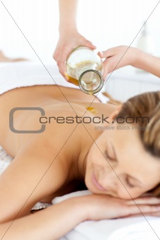 Glad young woman enjoying a back massage with oil 