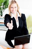 Postive businesswoman with thumb up using her laptop 