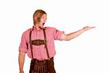 Bavarian man with oktoberfest leather trousers (lederhose) holds open hand for advertisement.