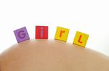 Word girl written with colorful alphabet cubes on pregnant belly