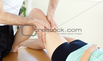 Caucasian young physical therapist giving a leg massage