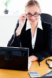 Charismatic businesswoman holding her glasses and using her lapt
