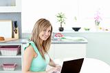 Delighted blond woman using her laptop smiling at the camera