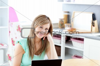 Joyful blond woman using her laptop smiling at the camera
