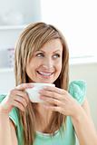 Charming caucasian woman holding a cup of coffee sitting in the 