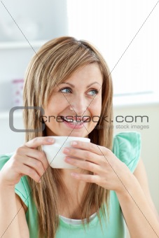 Charming caucasian woman holding a cup of coffee sitting in the 
