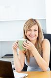 Attractive businesswoman holding a cup using her laptop 