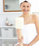 Merry woman holding a brush smiling at the camera 