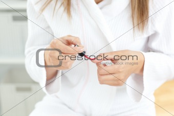 Close-up of a caucasian woman varnishing her fingernail 