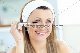Jolly young woman using mascara in the bathroom 