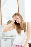 Dejected woman having a headache sitting in the bathroom 