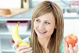 Positive caucasian woman holing a bananan and an apple 