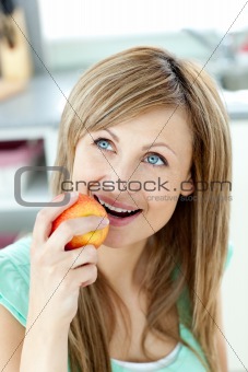 Captivating caucasian woman eating an apple in the kitchen