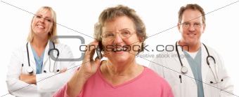 Happy Senior Woman Using Cell Phone with Male and Female Doctors or Nurses Behind Isolated on a White Background.