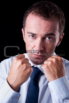 Businessman punching fist: sign of competition,  isolated on black, studio shot