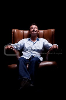 Man smiling and looking up seated on a chair