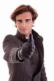 Portrait of a young businessman with thumb up, in autumn/winter clothes, isolated on white. Studio shot