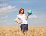 Young woman holding globe in wheat field