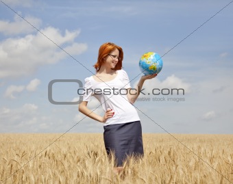 Young woman holding globe in wheat field