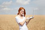 Young Businesswomen in white working with notebook at wheat fiel