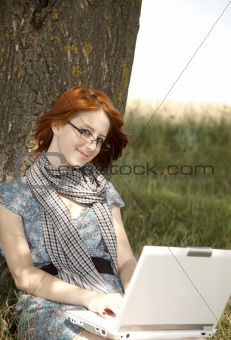 Young smiling fashion girl in glasses and notebook sitting near 