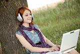 Young smiling fashion girl with notebook and headphones sitting 