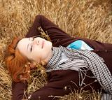 Young beautiful girl lying at yellow autumn field.