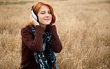 Young  smiling girl with headphones at field.