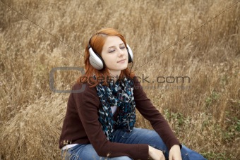 Young  smiling girl with headphones at field.