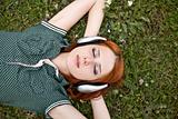 Young  fashion with headphones lying at green grass.