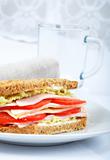fresh and delicious classic club sandwich over a white glass dish with glass cup