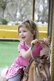 little blond girl playing horses merry go round
