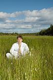 Young man meditates in a field