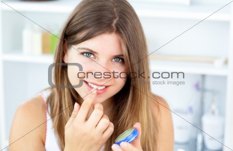 Pretty woman using vaseline for her lips in the bathroom