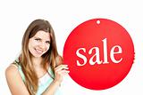 Bright young woman holding a red panel where "sale" is written