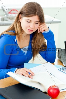 Jolly female teenager studying in the kitchen