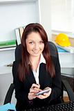 Positive businesswoman using her calculator sitting at her desk