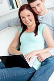 Loving couple using a laptop on a sofa