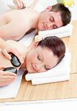 Lovely young couple receiving a back massage with hot stones